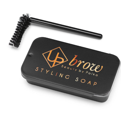 A small black aluminum box with 'UPbrow STYLING SOAP' text, alongside a curved brush for application.
