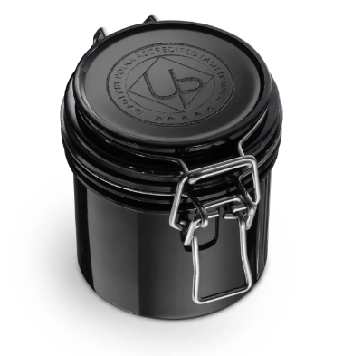 A black UPLashes glue storage container with a tightly sealed lid and a metal handle on the front.