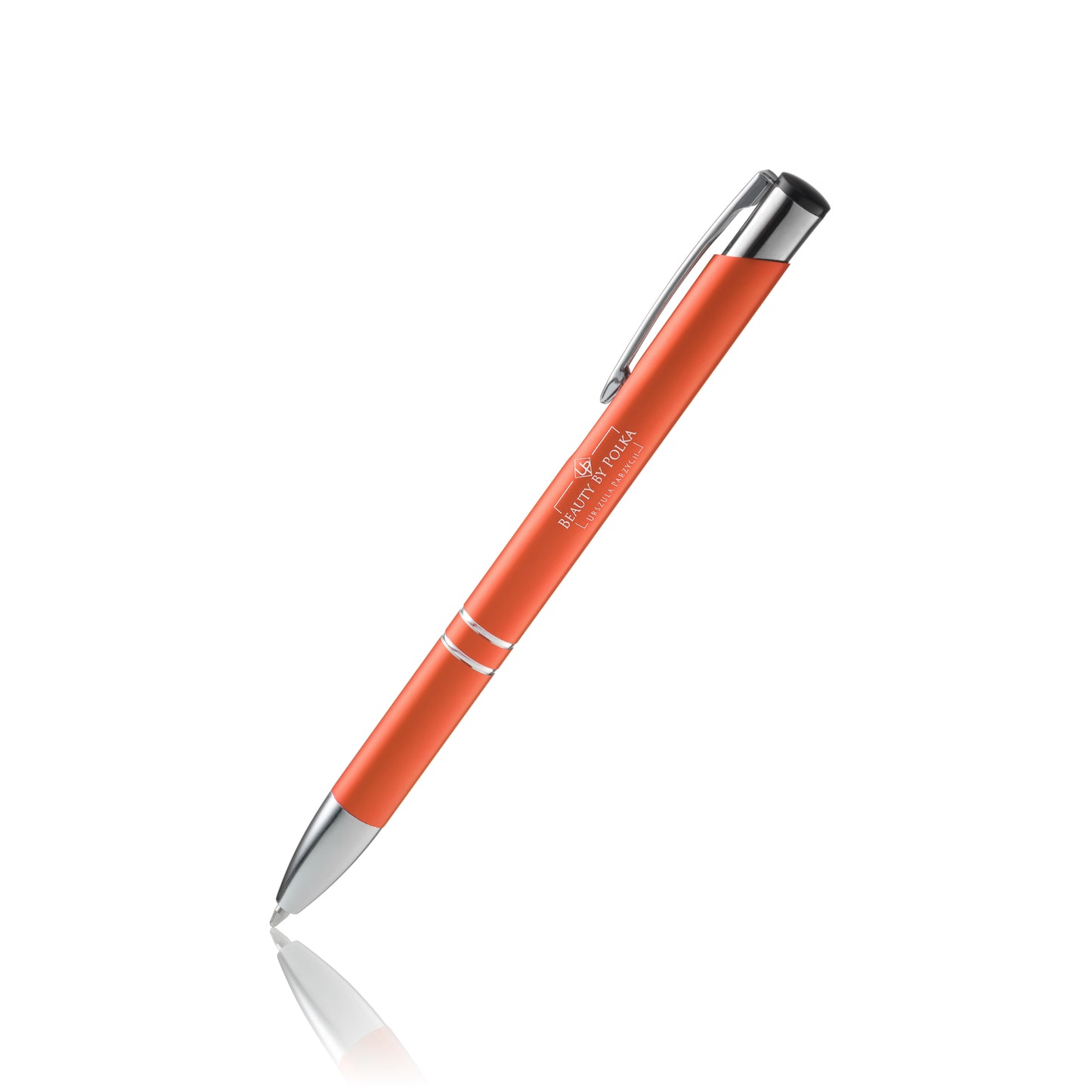 An engraved metal pen with an orange lacquered coating, silver accents, and a metal clip. The pen's model name is 'Beauty by Polka'.