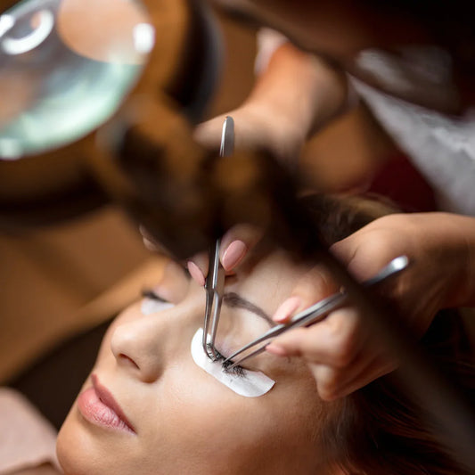 Eyelash procedure in progress with technician using dual tweezers