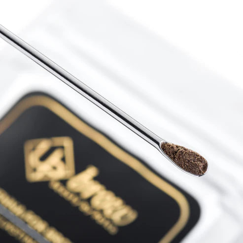 Metallic applicator with brown powder on a black and gold branded background