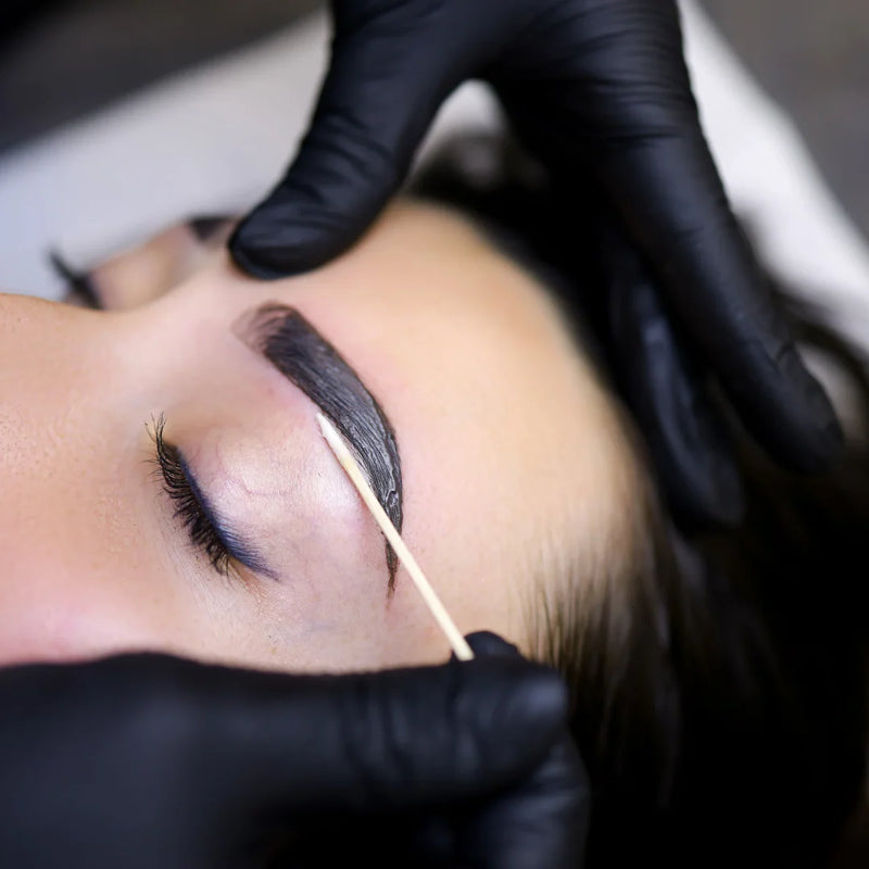 Close-up of brows being groomed and dyed with henna