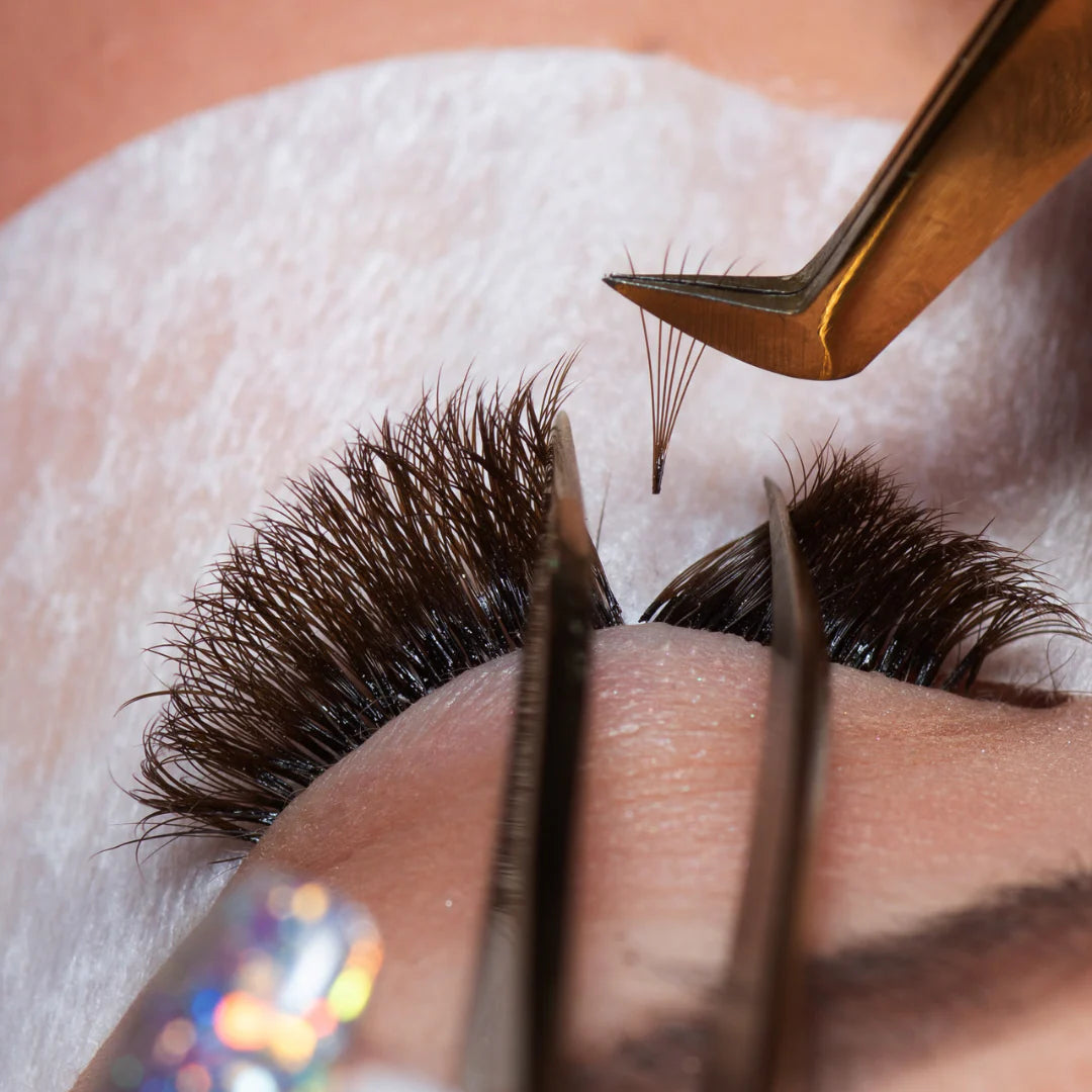Close-up of tweezers applying eyelash extensions for lash volume